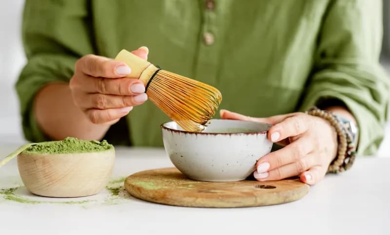 Frisch aufgeschlagener leuchtend grüner Matcha mit Bambusbesen